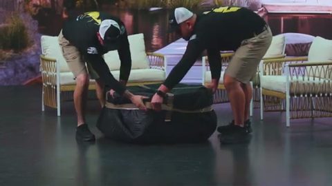 two movers strapping a blanket-wrapped patio furniture bundle